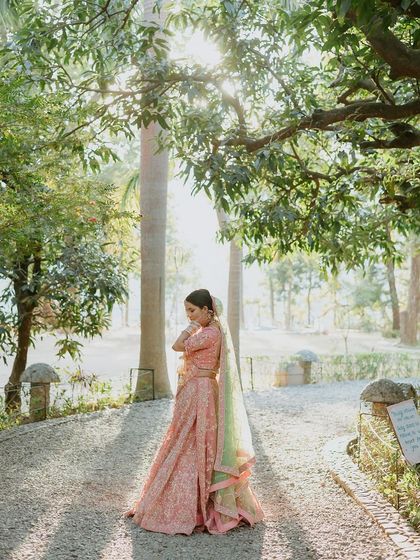 A bride stands in a pathway, backlit by the sun, creating a beautiful, ethereal glow around her.