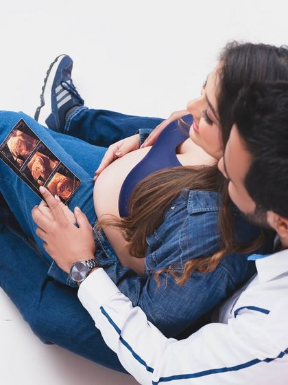 A casual and intimate moment, looking at the first photos of their little one. This overhead shot captures the couple's shared excitement and connection.