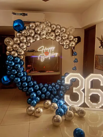 A stylish blue and silver theme for a 36th birthday. The decoration features a square balloon frame, a neon sign, and large light-up numbers.