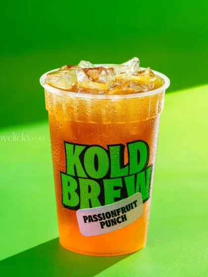 A passionfruit punch iced tea, shot with bright, sunny lighting against a green background.