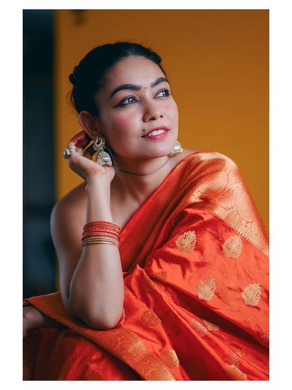 A vibrant portrait of a model in a bright orange saree. Her happy expression and the rich colors create a joyful and lively image.