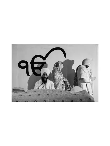 A black and white shot capturing a moment of prayer and reverence during a Sikh Anand Karaj ceremony.