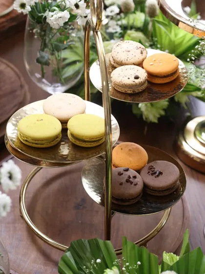 Our modern three-tiered gold high tea stand, elegantly displaying colorful macarons. Its minimalist design and hammered plates make it a chic addition to any celebration.