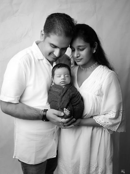 This black and white family portrait feels like a precious heirloom. The composition draws the eye to the tiny newborn cradled between the loving parents.