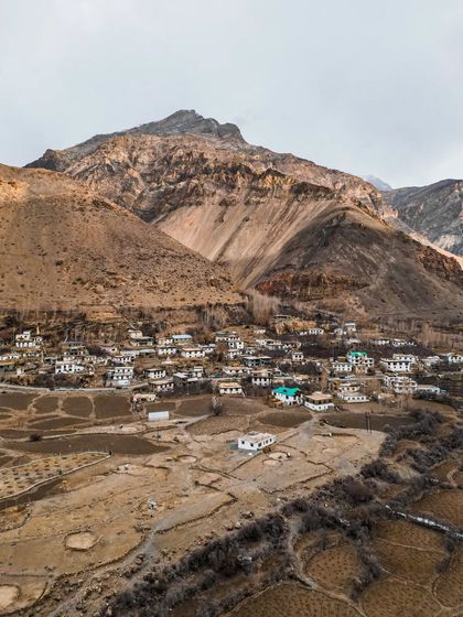 An aerial view of Poh village, nestled at the base of a massive mountain.