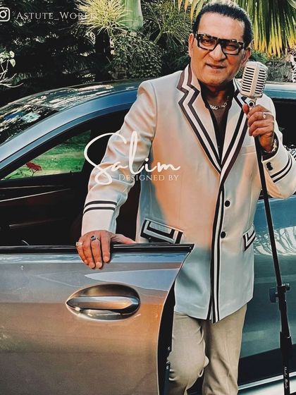 Singer Abhijeet Bhattacharya wearing a custom white suit with black trim details. This retro-inspired look was designed specifically for his stage persona.