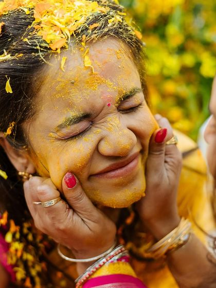 A close-up, candid shot of a guest playfully smearing turmeric on the bride's face.