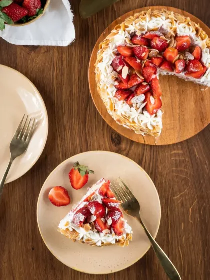 A slice of our Strawberry Almond Gateau served and ready to be enjoyed. It’s a light, airy cake with layers of cream, fresh strawberries, and toasted almonds.