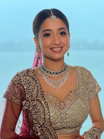 A smiling portrait of my bride by the water. The makeup is fresh and luminous, with a pop of emerald from her jewelry adding a touch of color.