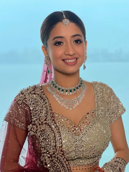 A smiling portrait of my bride by the water. The makeup is fresh and luminous, with a pop of emerald from her jewelry adding a touch of color.