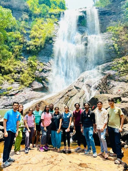 A group standing before the majestic Hebbe falls in Chikmagalur. Reaching this waterfall involves a cool jeep ride and a short hike, making it a complete adventure.