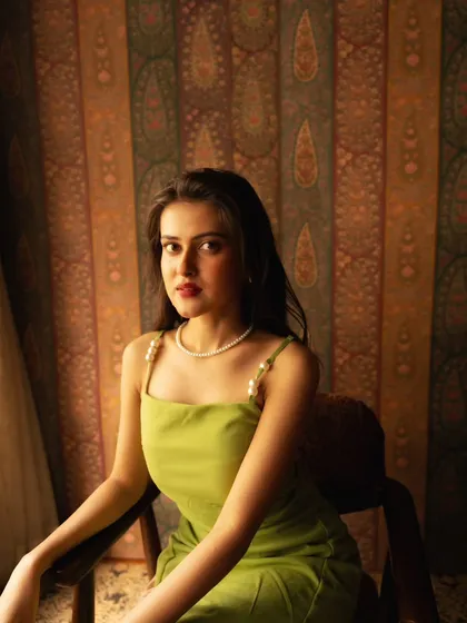 A simple, elegant portrait against a beautifully patterned backdrop. The natural light from the window provides a soft, flattering illumination.