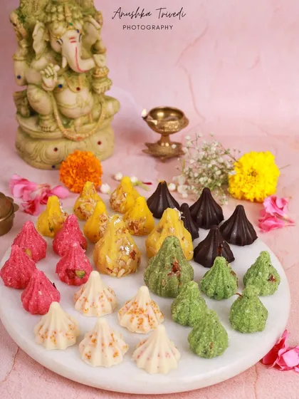 A platter of assorted colourful modaks, ready for a Ganesh Chaturthi celebration. The image is bright and joyful, capturing the festive spirit perfectly.