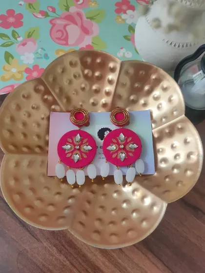 These bright pink hand-painted earrings are perfect for adding a pop of colour to your festive attire. They are decorated with kundan work and feature white bead drops.
