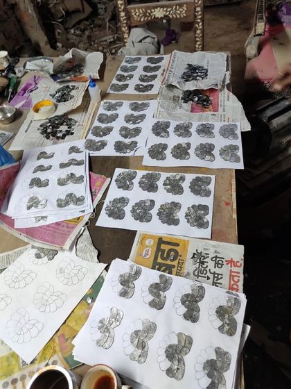 The artisan's workbench in Udaipur, covered with design templates and piles of cut glass. This image offers a behind-the-scenes look at the intricate and patient work required for Thikri craft.