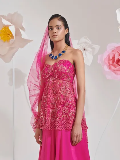 This look features a modern Indian ensemble in a bold fuchsia pink. I styled the embroidered peplum top and sharara pants with a sheer dupatta and a statement blue necklace to create a striking color contrast.