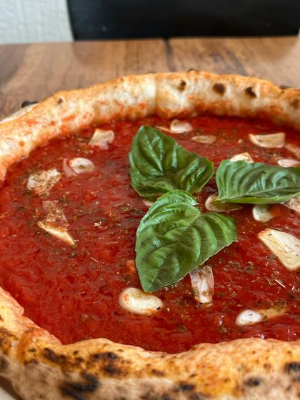 A close-up of our Marinara pizza, showing the fresh basil and garlic slices.