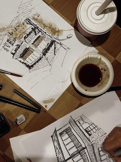 A top-down view of a workstation during one of my coffee painting workshops. You can see the sketch, the pens, and the cup of coffee used as paint.