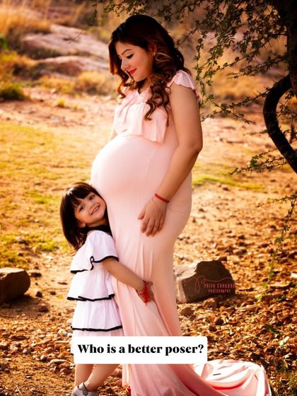 A daughter hugs her mother's baby bump. These are the tender moments that tell the story of a growing family, captured during a sunny outdoor maternity session.