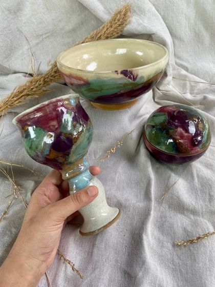 Another look at the prototypes, showcasing a lidded sphere, bowl, and goblet. The rich purple and green glazes create a painterly, abstract effect on the ceramic surface.