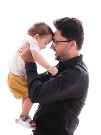 A father and son share an intimate forehead-to-forehead moment. This simple, clean portrait beautifully captures the deep connection and love between them.