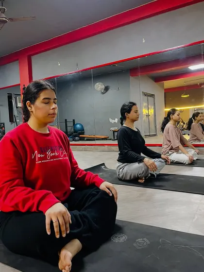A group of students finding their focus in a seated meditation pose during a studio class.