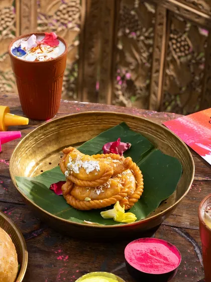 A plate of Gujiya, a traditional Holi sweet, beautifully garnished with silver leaf.