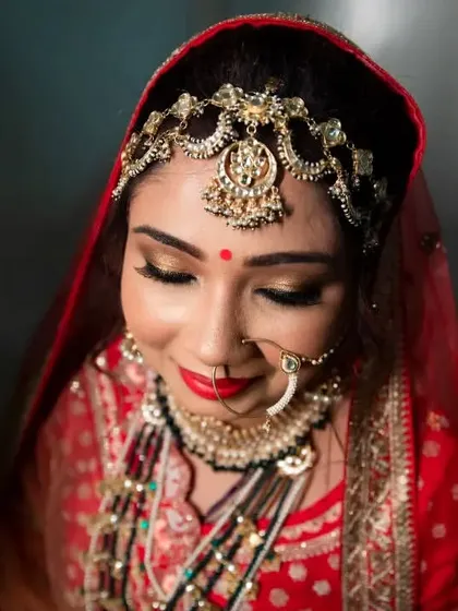 A beautiful high-angle shot of the bride in her red wedding lehenga, her eyes closed in a moment of serene contemplation.