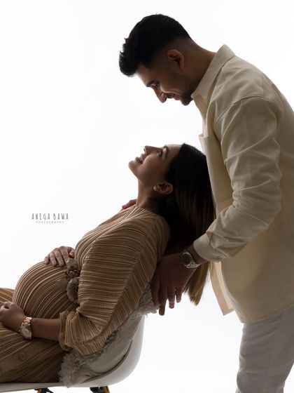 An artistic, high-contrast silhouette of an expecting couple. This image focuses on their connection and the beautiful shape of the baby bump.