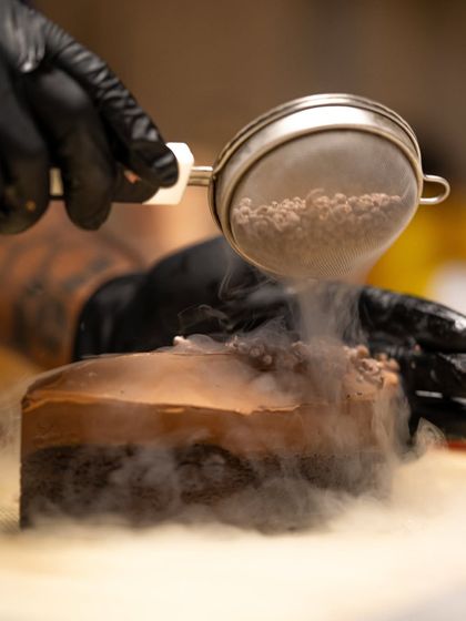 Using liquid nitrogen to create a dramatic, smoky effect while garnishing a chocolate dessert. We teach modern techniques to create stunning visual appeal.