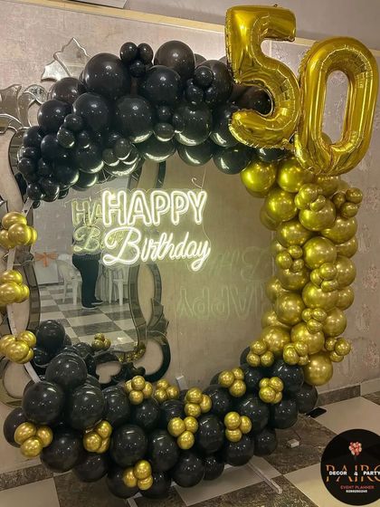 A bold black and gold balloon ring for a 50th birthday, set against a mirror for a dramatic effect.