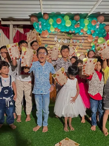 A proud group of kids showing off the lion paper bag puppets they made at a jungle-themed party. The craft activity is always a highlight.