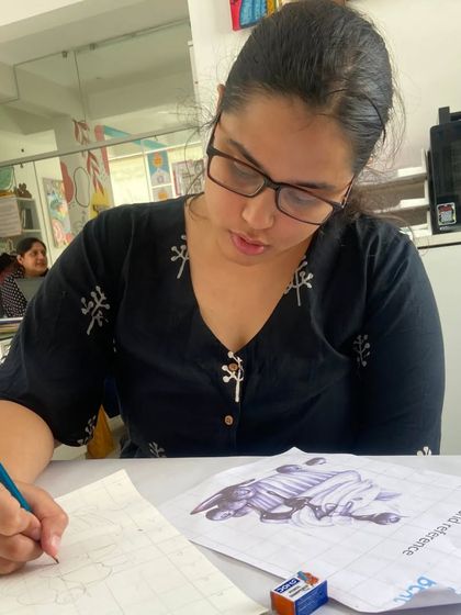 This student is using a reference image to guide her sketch, a common practice we encourage to improve observation skills.