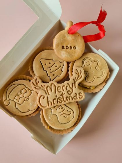 My Christmas Pies Box contains four wholesome pies with cute festive designs like Santa, a snowman, and a Christmas tree. Each box includes a 'Merry Christmas' cookie and a name tag ornament.
