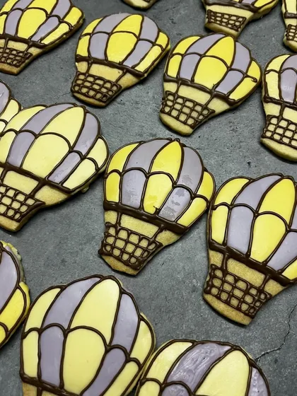 Up, up, and away! These hot air balloon cookies are perfect for a travel-themed party or a baby shower. The detailed line work is all done by hand.