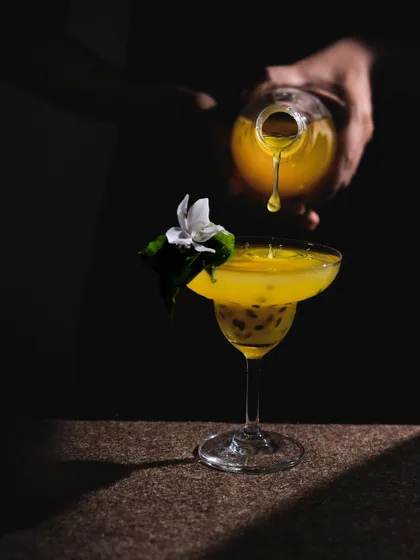 A classic dark and moody action shot of a drink being poured. The single, hard light source creates dramatic shadows and highlights the splash.