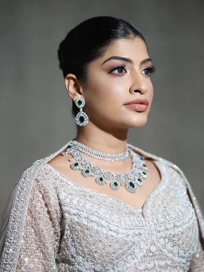 This close-up highlights the elegance of a layered zircon necklace with green gemstone drops. It's a piece that adds sophistication and sparkle to any reception or formal event outfit.