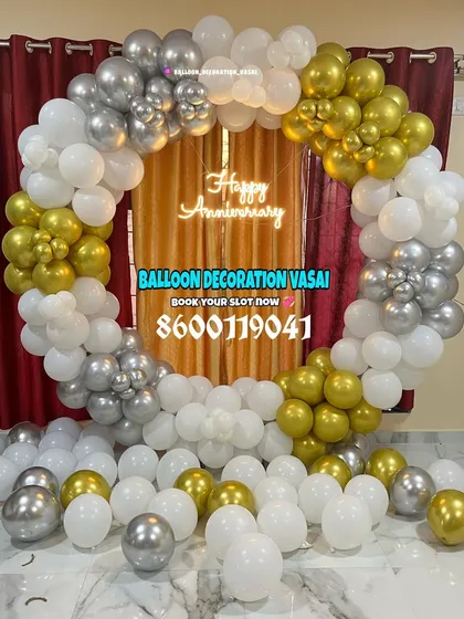 A classic anniversary balloon ring in white, silver, and gold. The balloons are arranged to create a full, lush circle with a "Happy Anniversary" neon sign glowing in the middle.