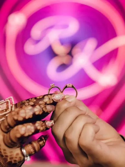 A close-up of the engagement rings, held against the backdrop of their custom monogram. This shot focuses on the ultimate symbol of commitment, a small detail that holds the entire story of a promise.