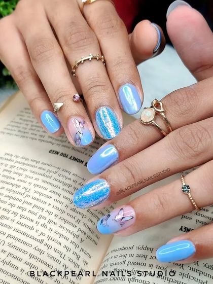 A full view of the butterfly and glitter nail set, showcasing the combination of chrome, sparkle, and delicate art.