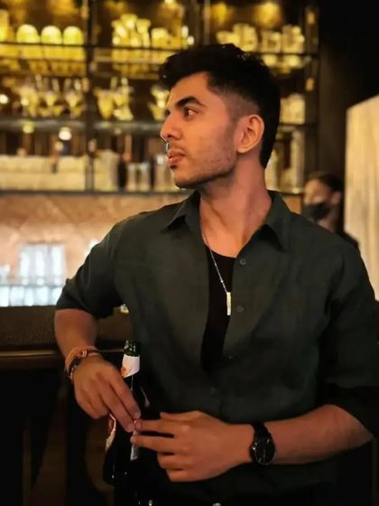 A man in a stylish setting wearing a silver-toned bar pendant. This image showcases the necklace as a fashionable accessory for a night out.