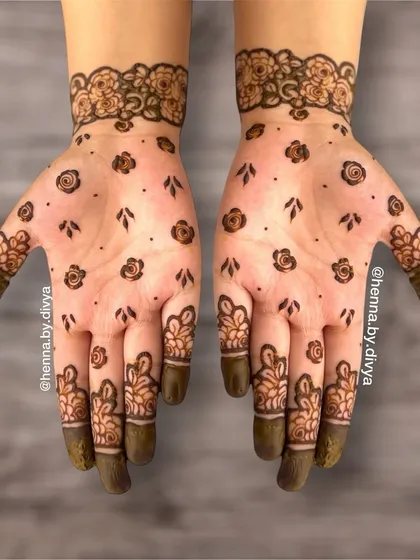 This fancy henna design is perfect for a party. It features scattered floral bootis on the palm with more detailed floral work on the fingers and a matching cuff, combining simplicity with intricacy.