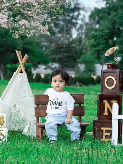 A classic picnic setup for a first birthday, with a teepee, wooden blocks, and a happy baby.