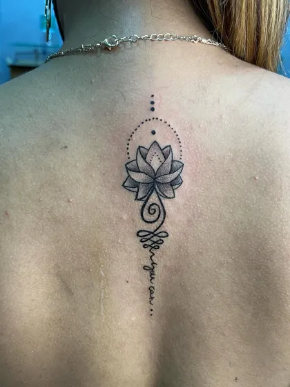 A beautiful unalome and lotus tattoo on the back. This Buddhist symbol represents the path to enlightenment and is a very popular spiritual design.