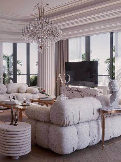 A contemporary take on classical living, this space features clean lines and modern furniture forms. The design is unified by traditional elements like fluted columns, a grand crystal chandelier, and a muted color palette, achieving a harmonious and relaxed environment.
