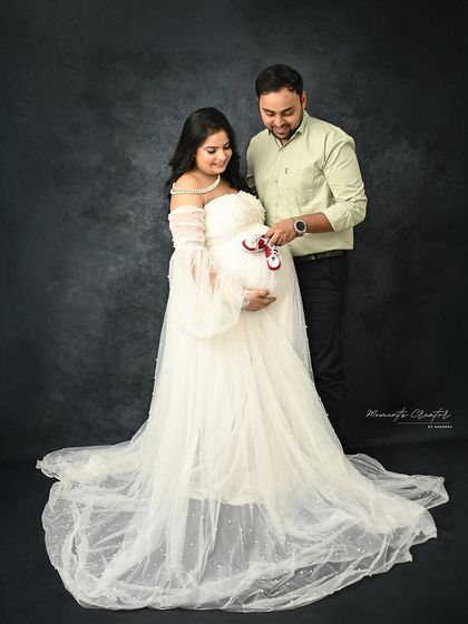 A sweet and simple couple's portrait. The dad-to-be playfully places tiny baby shoes on the bump, a charming detail that adds personality to the shot.