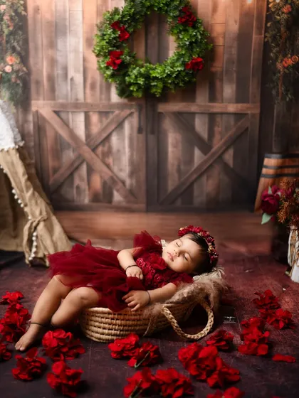 Even a nap can be beautiful. A peaceful moment of a baby sleeping in a basket, surrounded by red flowers.