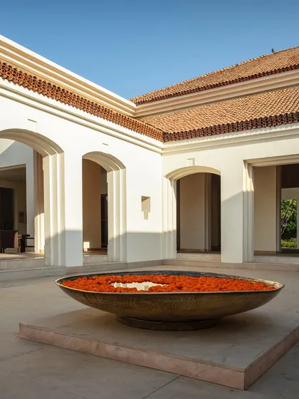 A central courtyard offers a moment of profound peace and welcome. The traditional brass 'urli' filled with flowers, set against the clean lines of modern arches, symbolizes our approach: a seamless blend of timeless Indian heritage and contemporary architectural thought.