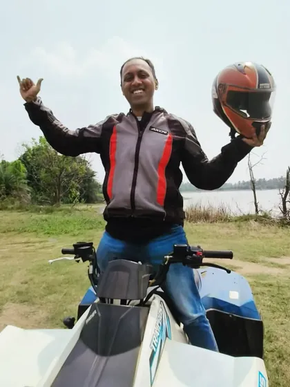 The pure joy of conquering the trail. This rider from Hyderabad celebrates with a big smile and a shaka sign after an awesome off-road session by the lake.