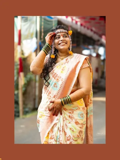 A full-length portrait of the bride during her Haldi. Capturing her in the outdoor setting of her home in Raigad adds a personal touch. Her expression of looking up with a smile is a beautiful, candid moment of hope and happiness.